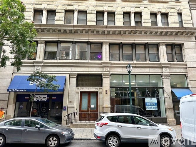 A silver car is parked in front of a building with a blue awning.