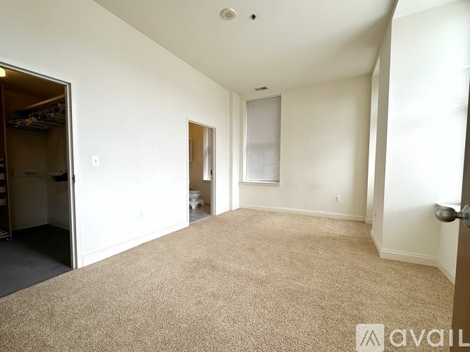 A carpeted room with a door and a window.