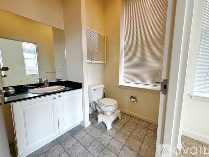 A white toilet sits in a bathroom with a black counter top.