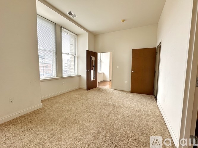 A carpeted room with a door and a window.