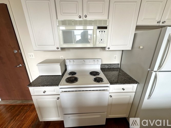 A kitchen with white cabinets and a black countertop.