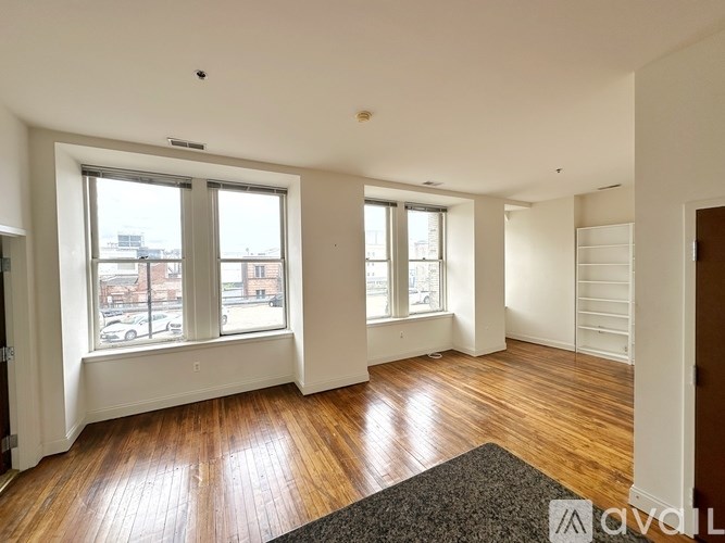 A living room with wooden floors and large windows.