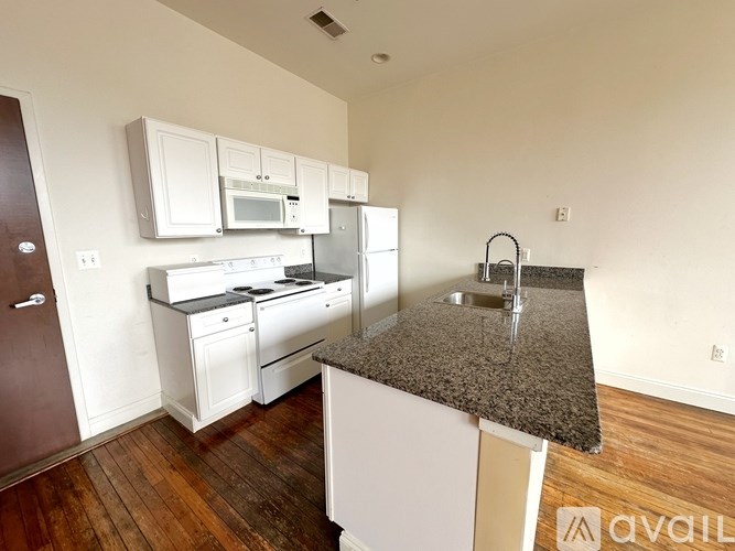 A kitchen with white cabinets and a granite countertop.