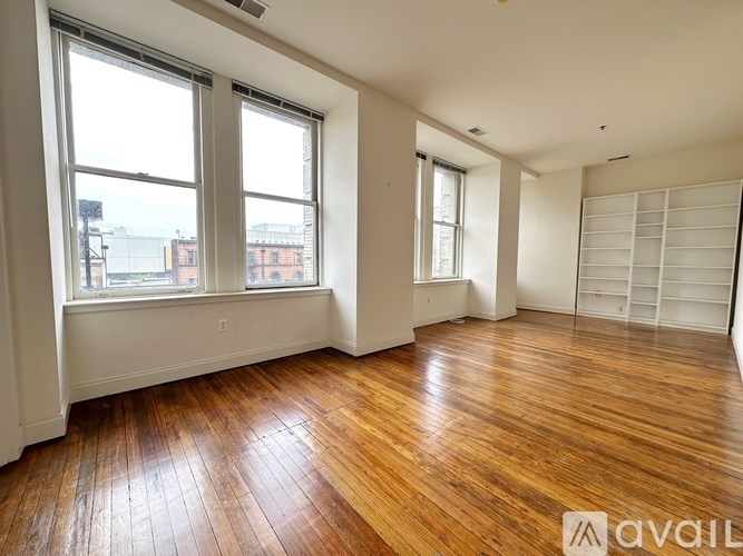 A room with wooden floors and two windows.