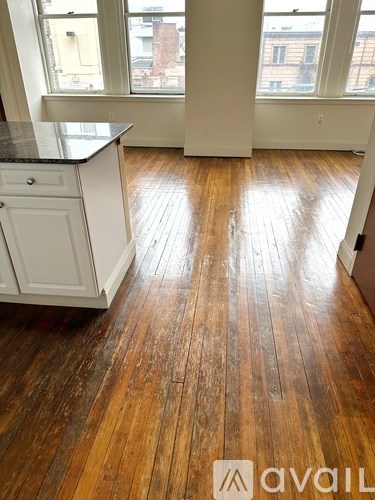 A room with wooden floors and a kitchen area.