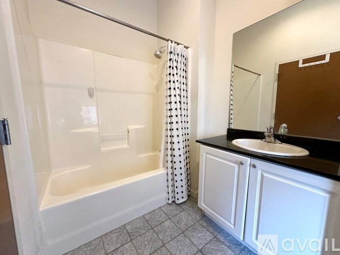 A white bathroom with a black counter top and a white sink.
