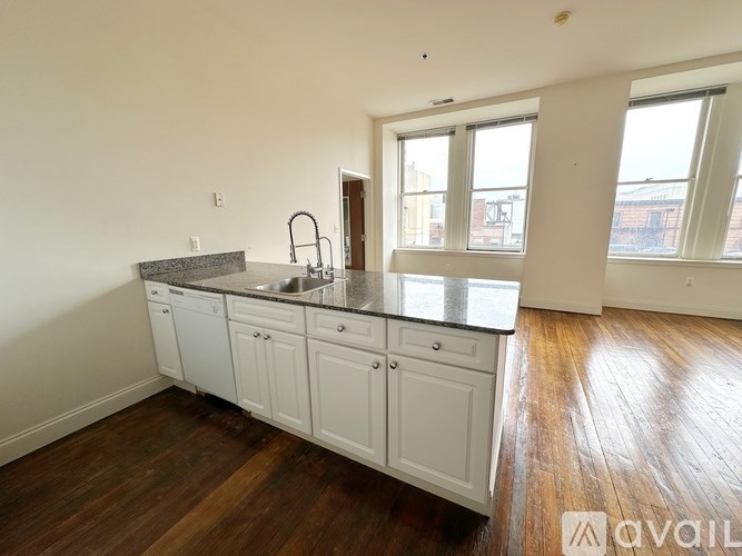 A kitchen with white cabinets and a black countertop.