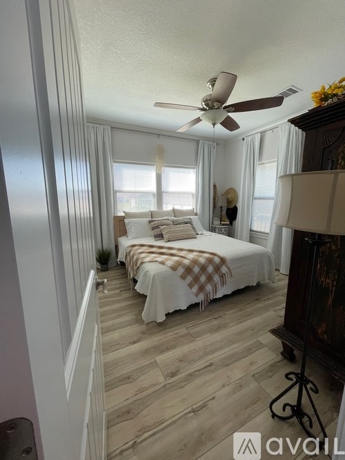 A bedroom with a bed covered in a plaid comforter and a ceiling fan.