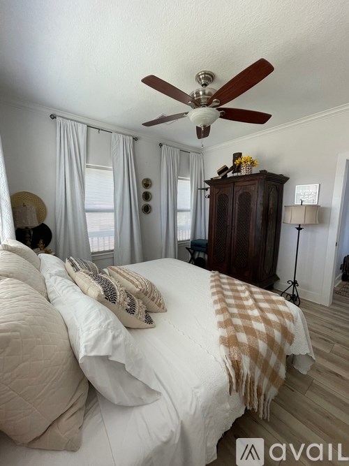 A bedroom with a large bed and a ceiling fan.