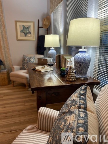 A living room with a sofa, a table with a lamp and a vase on it.