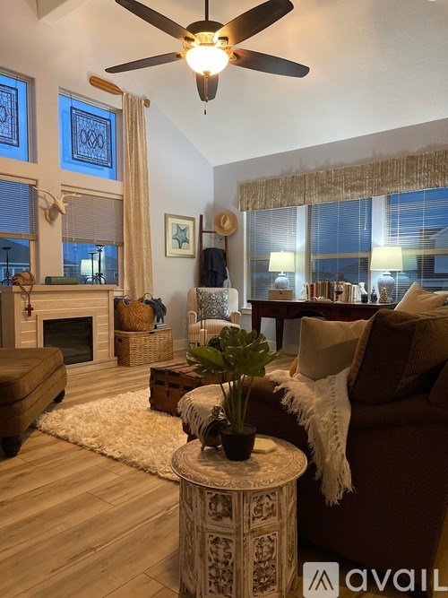 A living room with a fireplace, a couch, and a ceiling fan.