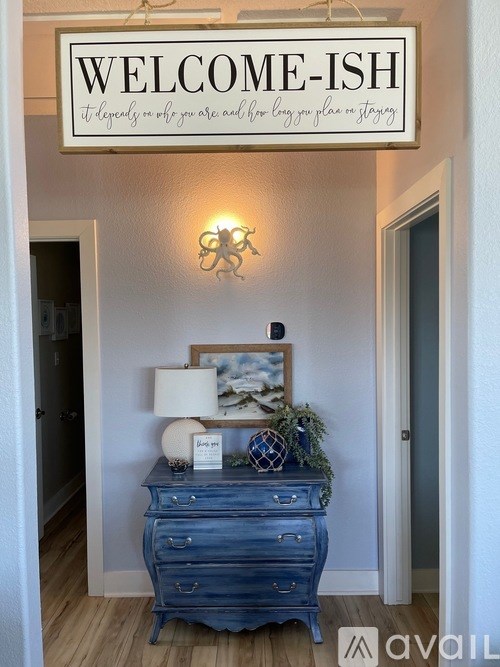 A blue dresser is in front of a wall with a sign that says "WELCOME-ISH".