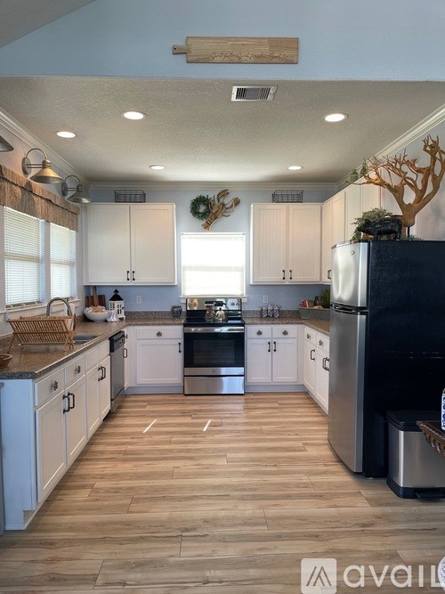 A kitchen with wooden floors and white cabinets.