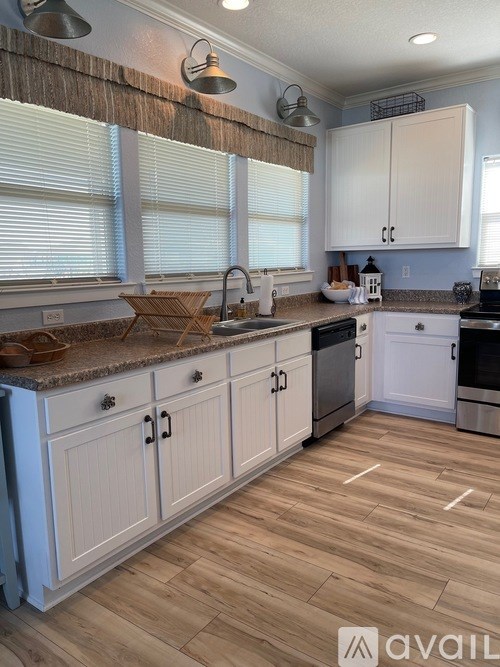 A kitchen with wooden floors and white cabinets.