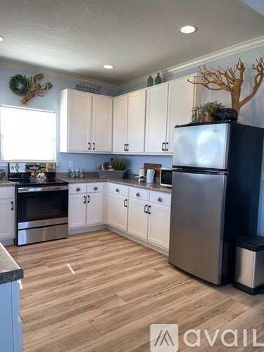 A kitchen with a black fridge and wooden floors.