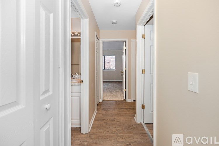 A hallway with white doors and a light switch on the wall.