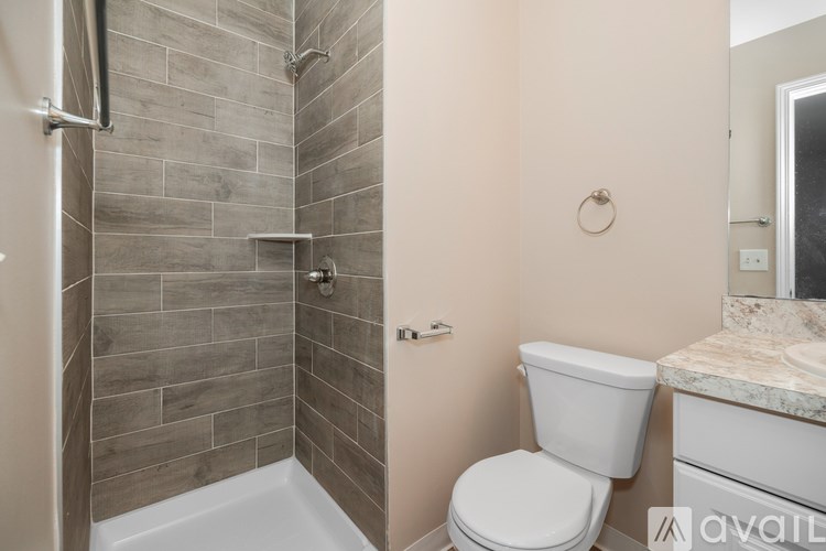 A bathroom with a toilet, sink, and tiled shower.