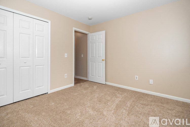 A room with a carpeted floor, two doors, and a wall-mounted light fixture.