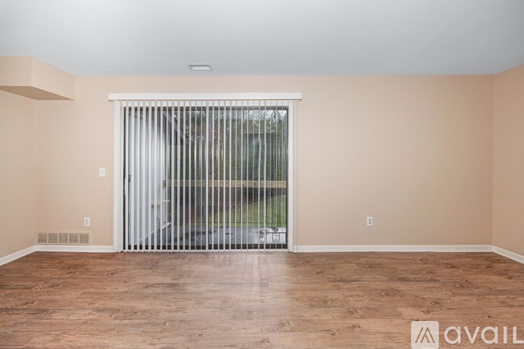 A room with wooden flooring and a sliding glass door.