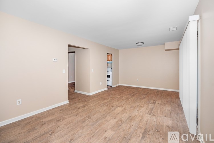 A spacious room with wooden flooring and a white door in the background.