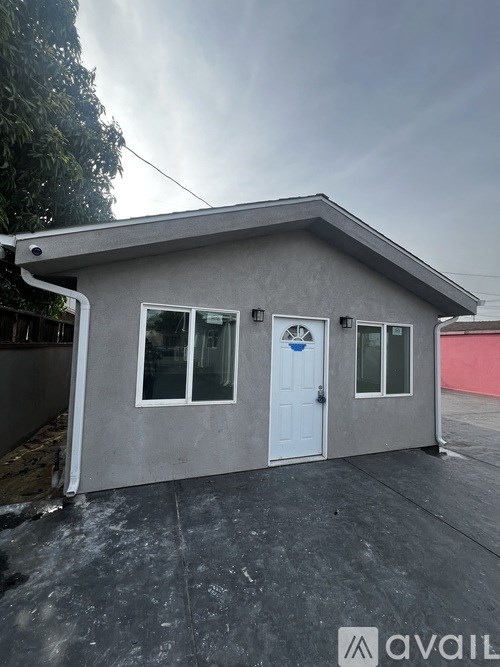 A small grey house with a white door and windows.