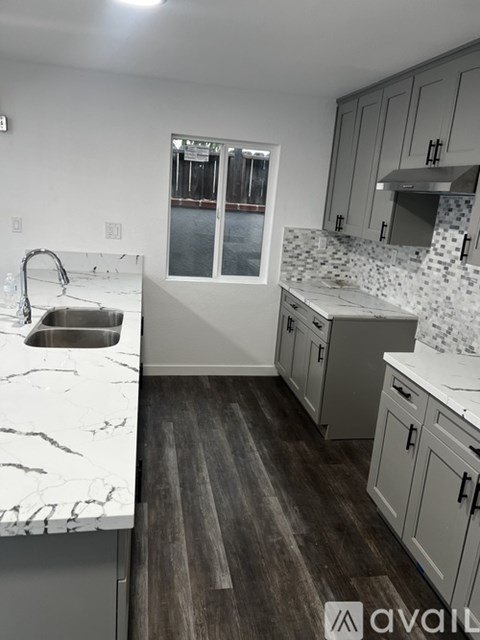 A kitchen with a marble countertop and wooden flooring.
