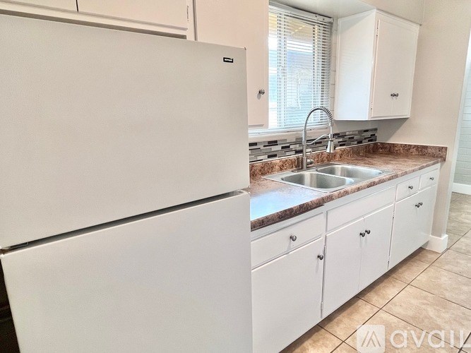 A kitchen with a white refrigerator and cabinets.