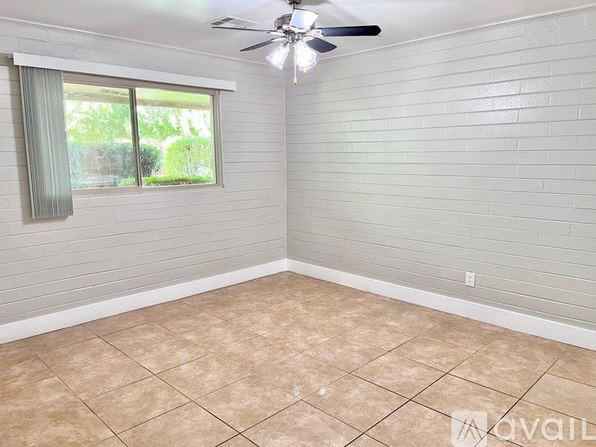 A room with a ceiling fan and a window with a view of greenery outside.