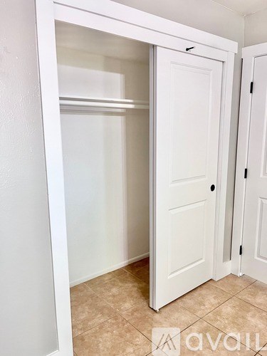 A white door is open to a room with tiled flooring.
