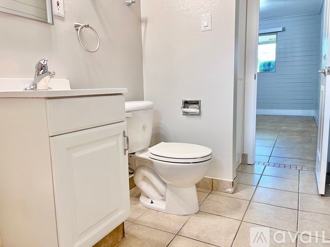 A white toilet in a bathroom with a white sink and a white cabinet.