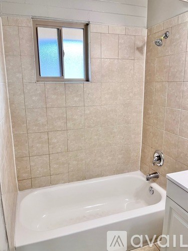 A bathroom with a white tub and a window.