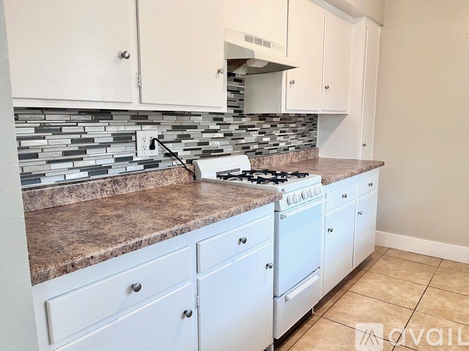 A kitchen with a white stove and cabinets.