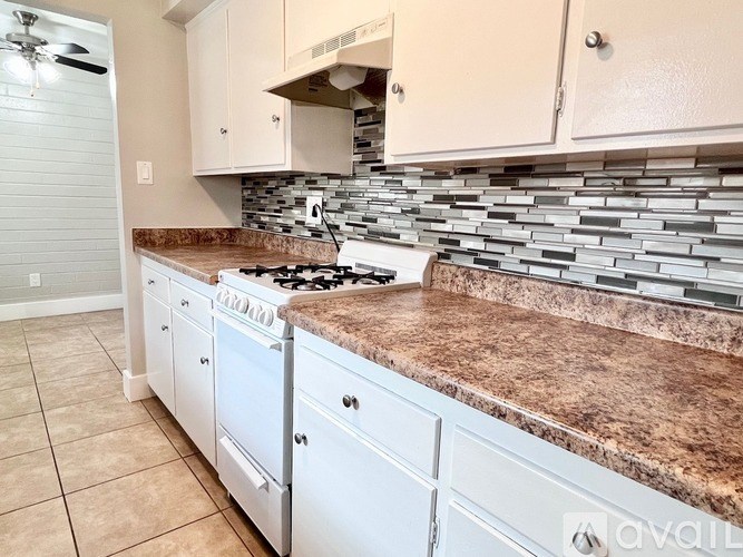 A kitchen with a marble countertop and white cabinets.