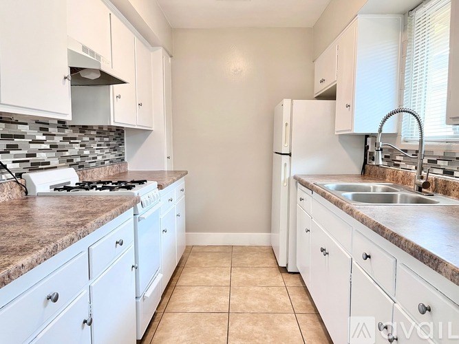 A kitchen with white cabinets and a stone backsplash.