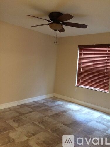 A room with a ceiling fan and a window with blinds.
