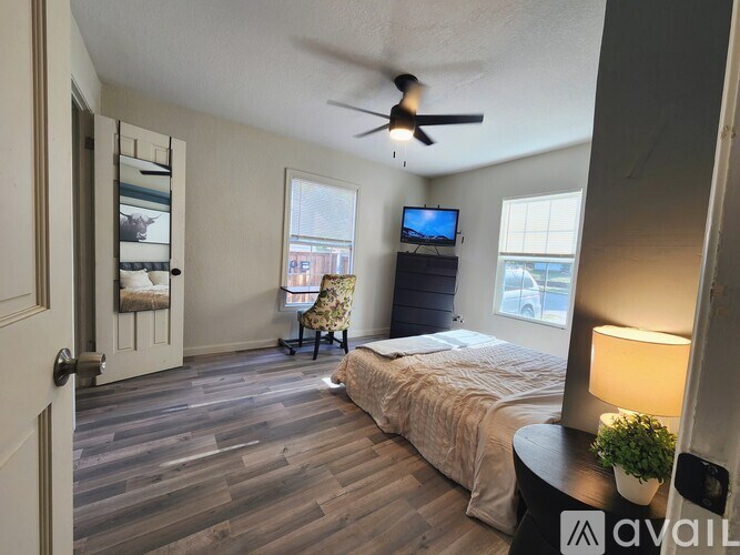 A bedroom with a bed, a chair, a ceiling fan, and a window.