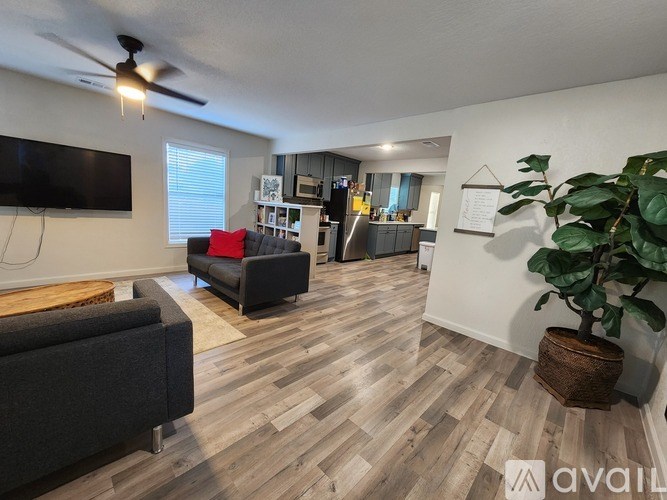 A living room with a black couch and a wooden floor.