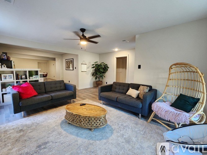 A living room with a grey couch, a wooden coffee table, and a hanging chair.