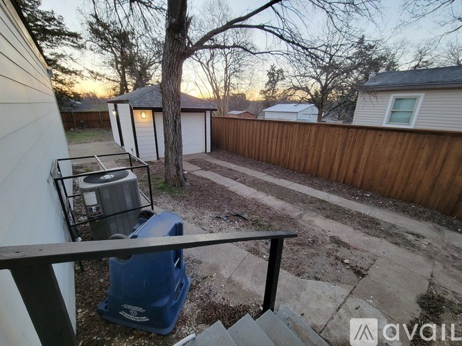 A backyard with a blue chair and a wooden fence.
