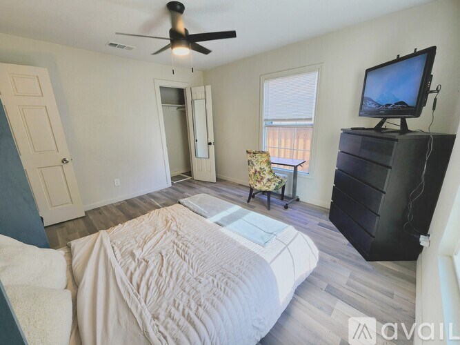 A bedroom with a large bed and a television on a dresser.