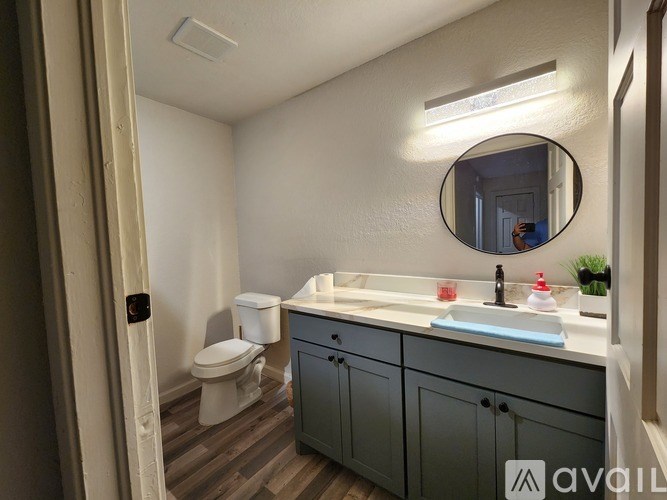 A bathroom with a toilet, sink, and mirror.
