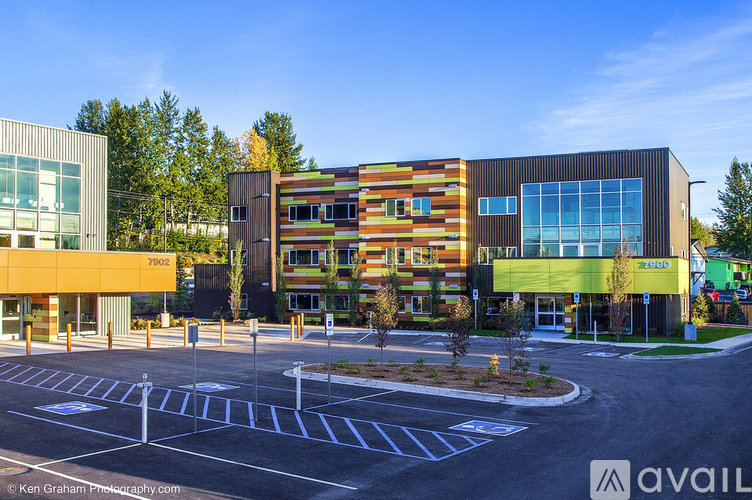 A modern building with a glass facade and a parking lot in front.