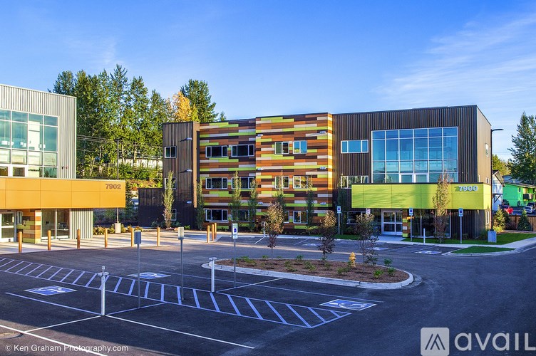 A modern building with a glass facade and a parking lot in front.