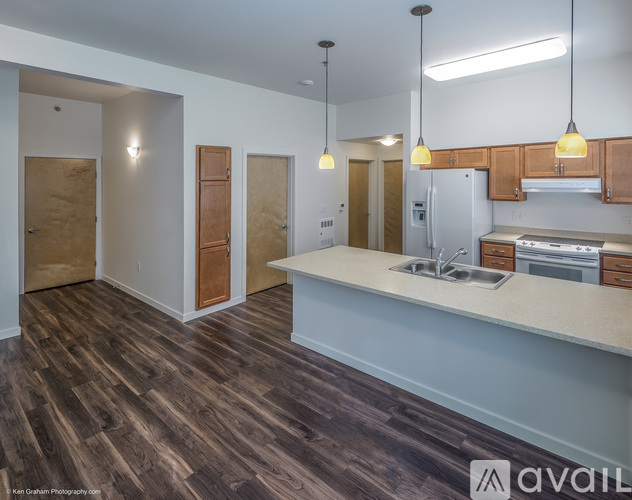A kitchen with wooden floors and a countertop with a sink and stove.