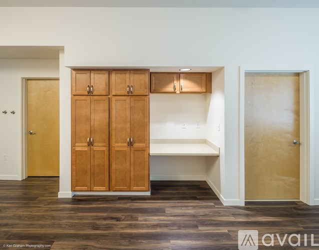 A room with wooden floors and a set of wooden cabinets with a bench underneath.