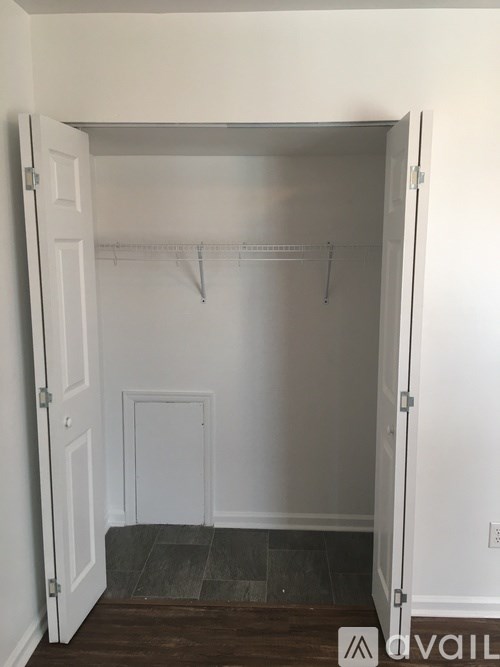 A white closet with a grey floor and a white door.