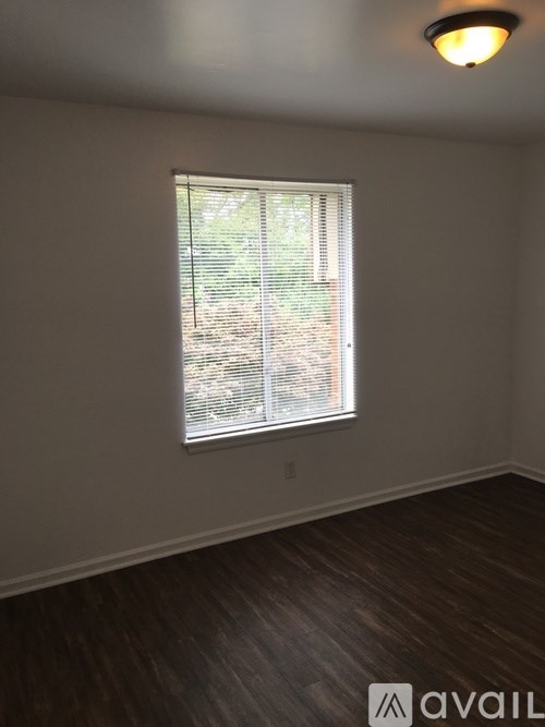 A room with a window covered by white blinds.