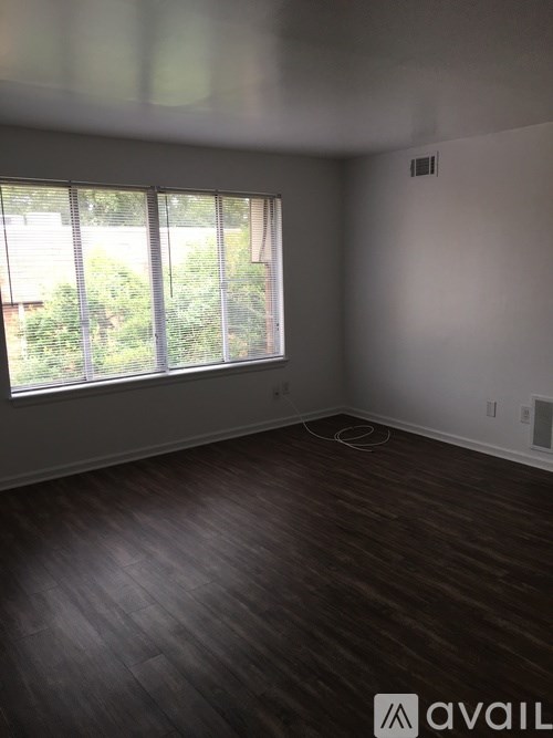 A room with wooden flooring and a window with blinds.