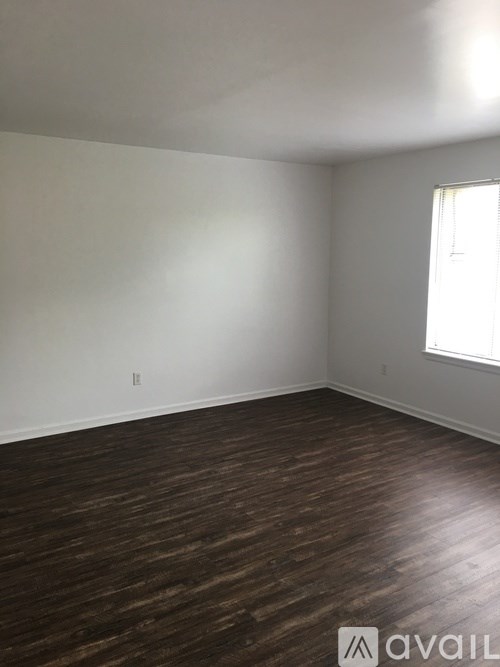A room with wooden flooring and a window letting in natural light.