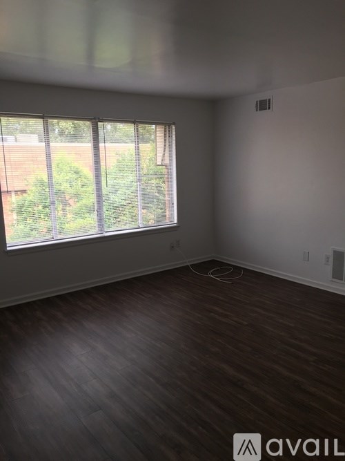 A room with wooden flooring and a large window.